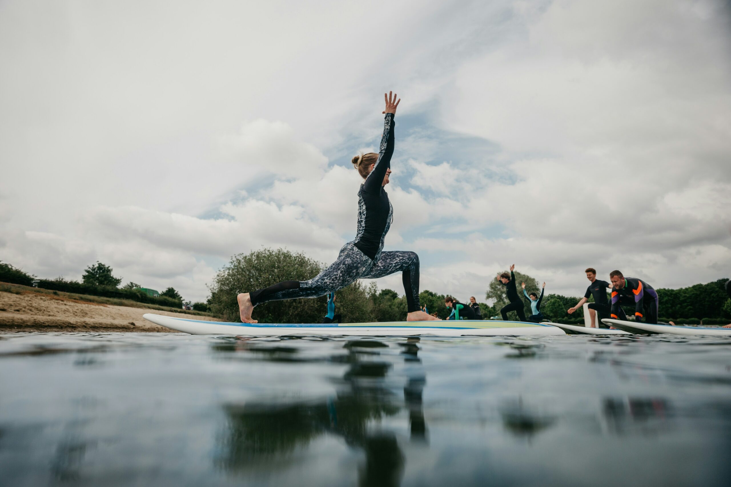 Woman Practicing High Lunge Pose During SUP Yoga Class Woman Practicing High Lunge Pose During SUP Yoga Class