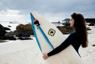 Female Surfer Holding Board on Rocky Australian Beach